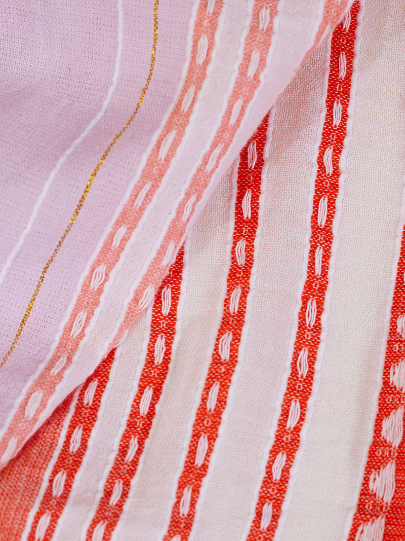 Close up on the fabric of the Eshal Short Plunge Neck Dress featuring white doted stripes with gradiant orange and tangerine bands on a lilac and white background.