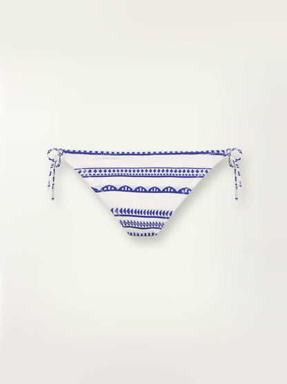 Product shot of the Yani String Bikini Bottom featuring blue tibeb diamond design bands on a textured seersucker white background.  