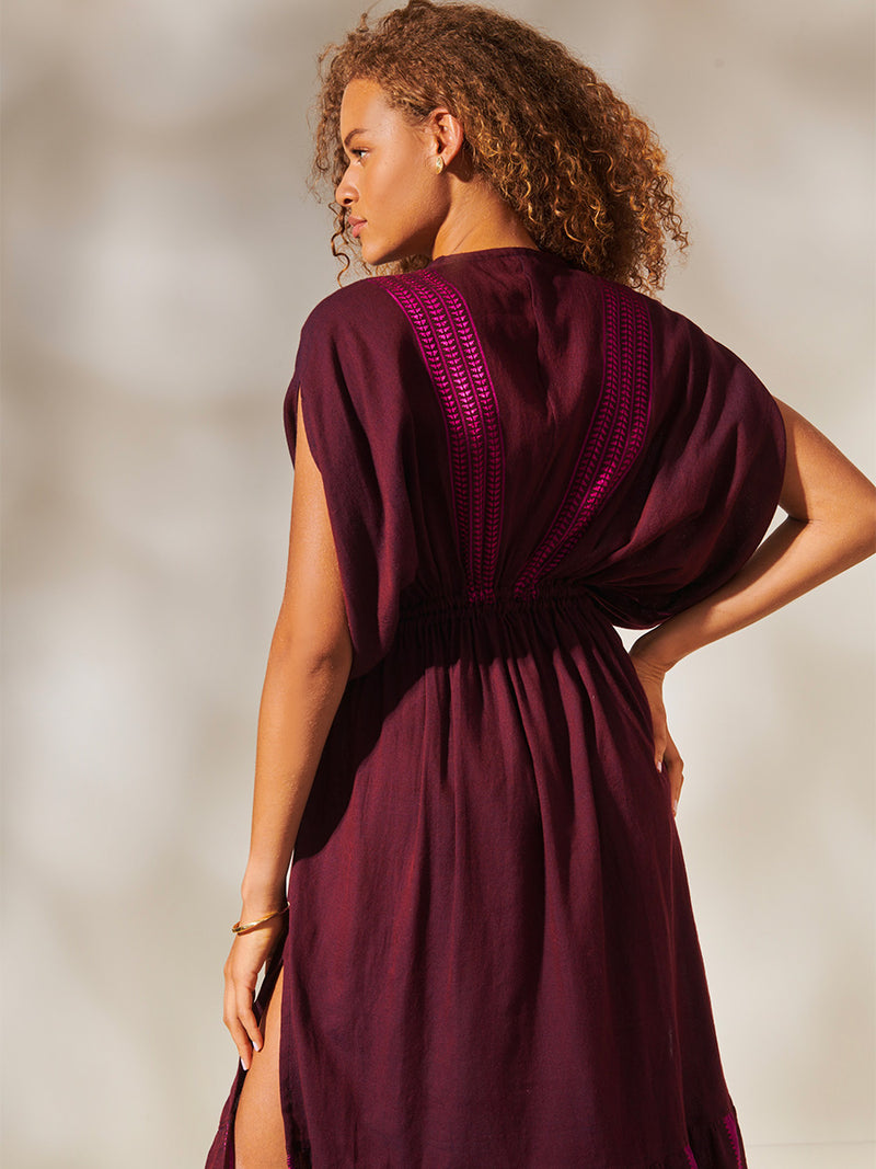 Back of a Woman Standing Wearing Leila Plunge Dress featuring rich, luxurious burgundy tones with hints of magenta.