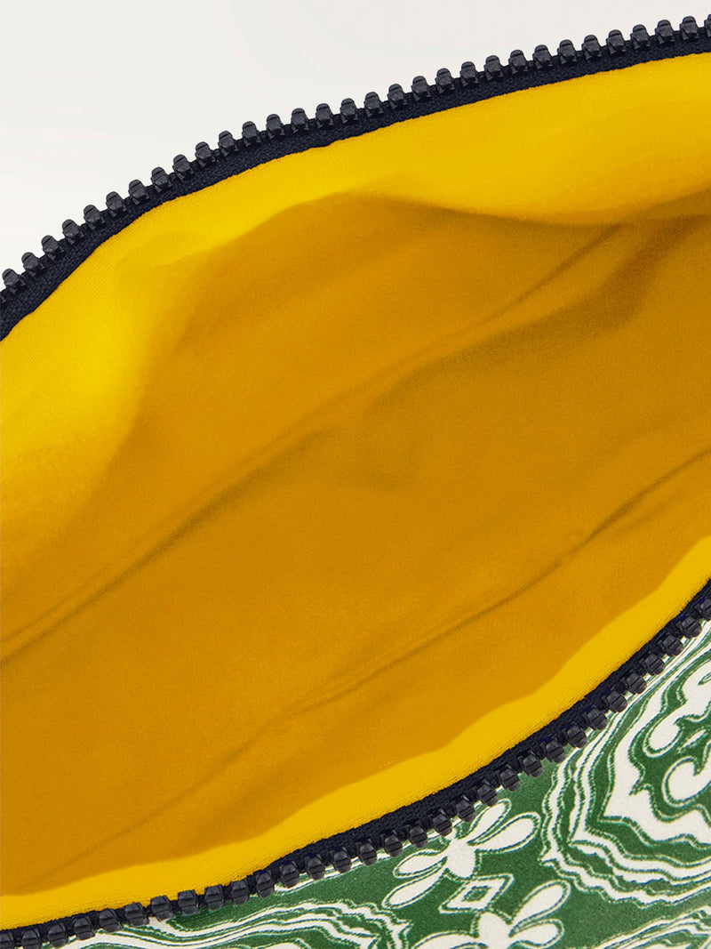 Inside lined in yellow of a green travel pouch featuring all over medallion pattern and a black zip closure at the top.