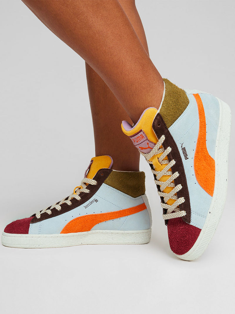 Close Up on a Woman Standing Wearing Puma x lemlem Suede Sneakers in Icy Blue Color featuring Color Accents in Olive, Red and Cayenne Pepper Colors