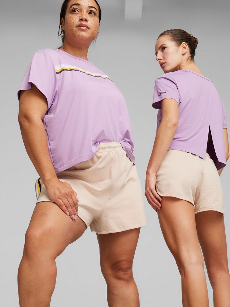 Two Women Standing Wearing Puma x lemlem Tee in Vivid Violet Color featuring color stripe detail on the front