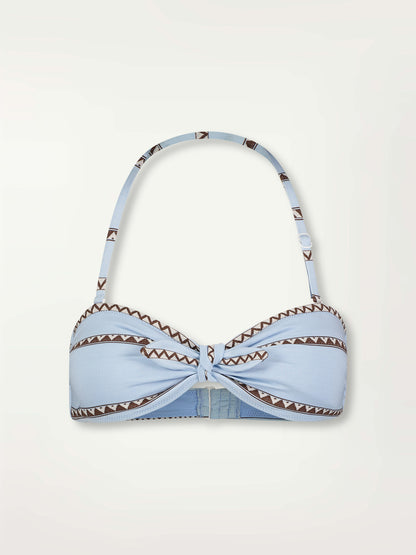 Product Front Shot of an AVA Bandeau Top featuring  intricate bands of dark earth and ivory Tibeb patterning on a pale sky blue background.