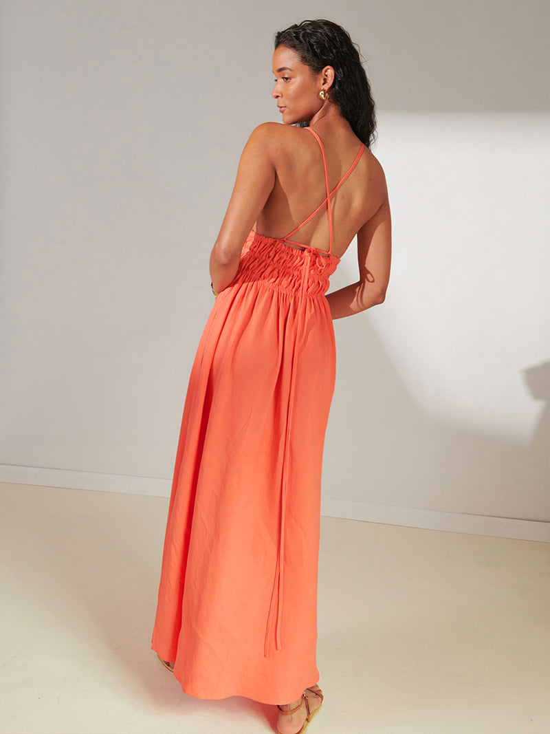 Back View of a Woman Standing Wearing lemlem Gete Triangle Dress in Coral Color