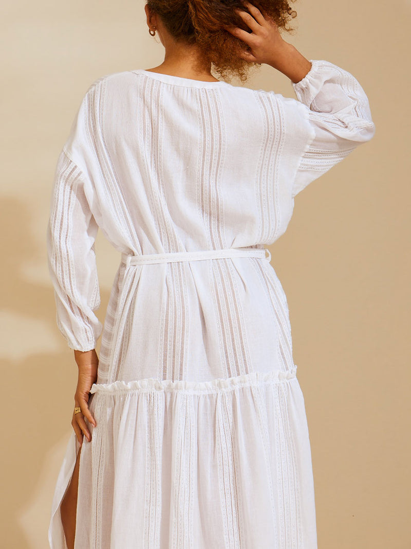 Back view of a woman standing wearing a white Abira Poet Shirt Dress with stitches of silver lurex