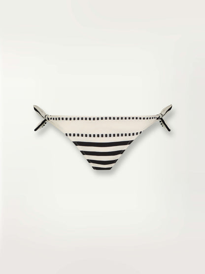 Product shot of the Eshe Side Tie Bikini Bottom featuring architectural and textured black stripes and dotted lines on an off white background.