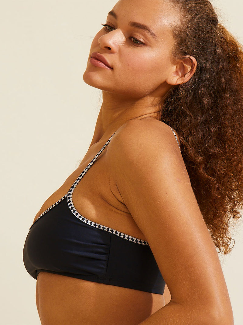 Close up on a woman wearing the Lena Bralette Top in Black featuring black and white tibeb straps