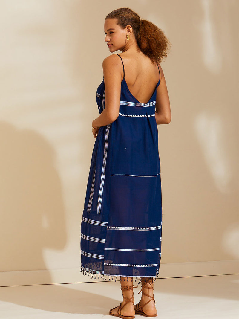 Back view of a woman standing wearing the Nunu Long Slip Dress in navy blue featuring white stripes and graphic lines.