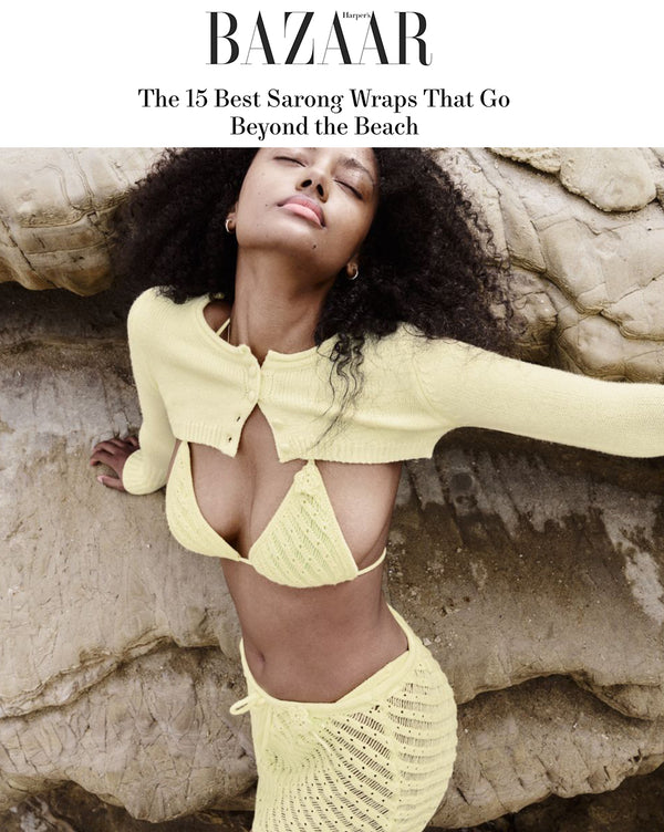 woman posing on a rock for the Vogue cover, dressed in a yellow crochet ensemble, including a long skirt, a bikini top, and a cropped cardigan.