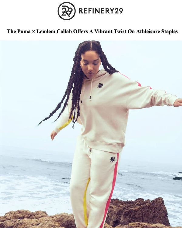 A woman on rocks by the sea, wearing joggers and a hoodie from the Lemlem x Puma collaboration that remixes classic Puma sportswear with hand-sketched Lemlem designs.