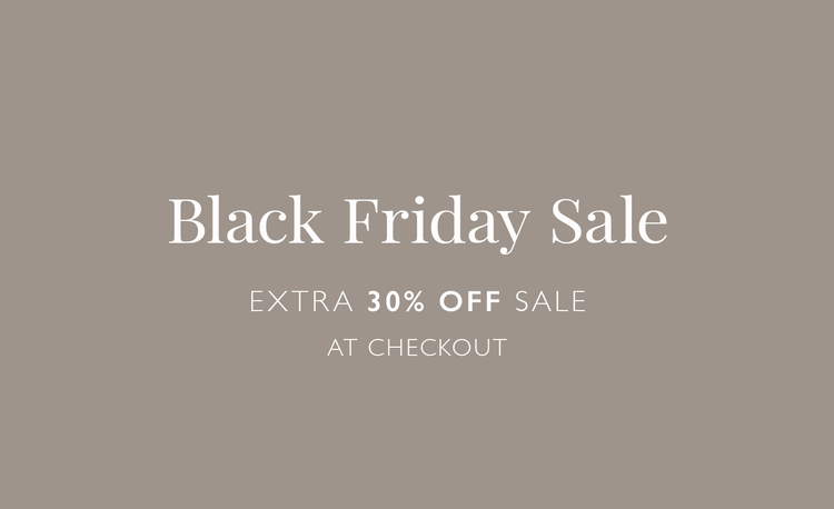 Woman Walking on the beach wearing lemlem plunge dress featruring dotted stripe pattern in orange color on pale blue background