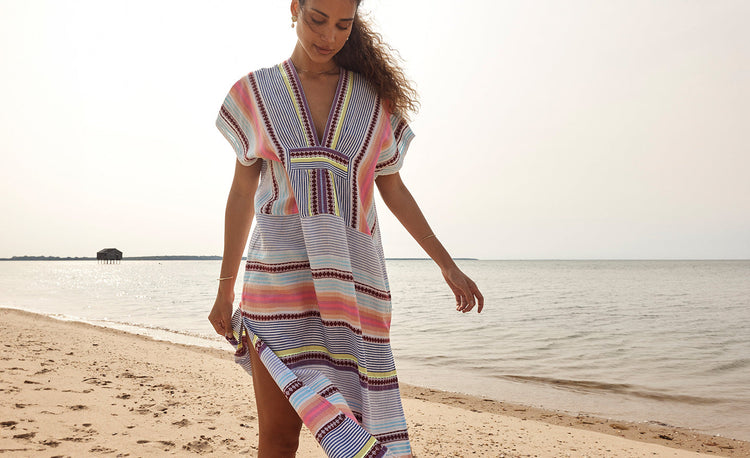 Woman Standing Wearing lemlem one piece swimsuit and lemlem handwoven jacket featuring multi tibeb pattern in different colors