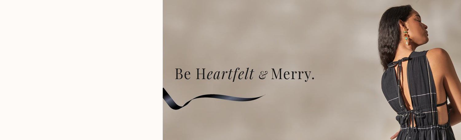 Holiday Message "Be Heartfelt & Merry" on a beuge background with a woman standing back facing wearing a black dress.