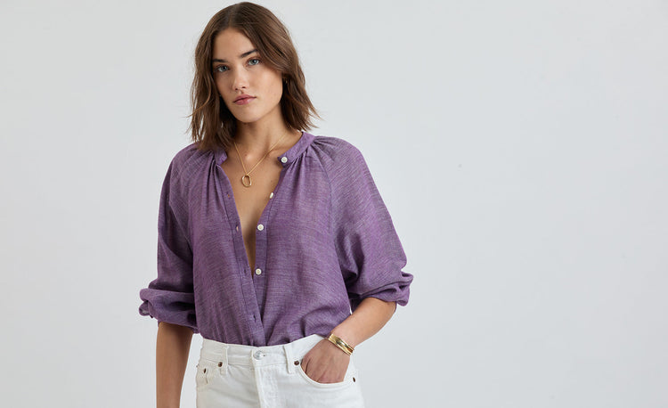 Woman wearing a Mita Plum button up blouse with white denim