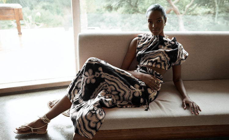 Woman sitting on the couch wearing lemlem Cropped Top and Maxi Skirt featuring print in black and cream colors