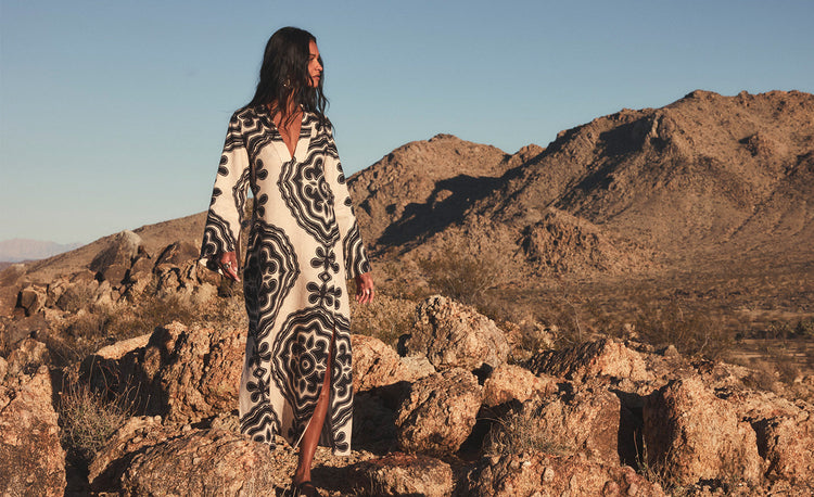 Woman Standing wearing lemlem linen skirt and matching top featuring black ancient inspired print on cream background