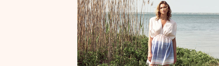 Woman standing on a beach in Fire Island wearing the Jelba short plunge neck dress in light pink and blue