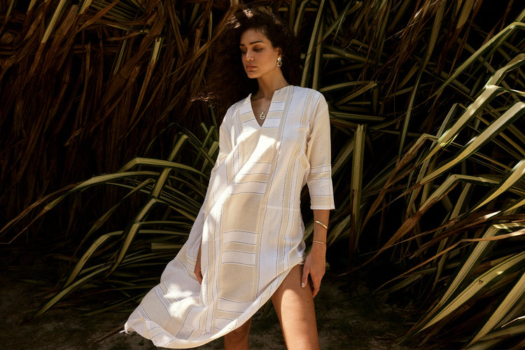 Woman Standing wearing lemlem handwoven v neck dress featuring black color and white tibeb pattern