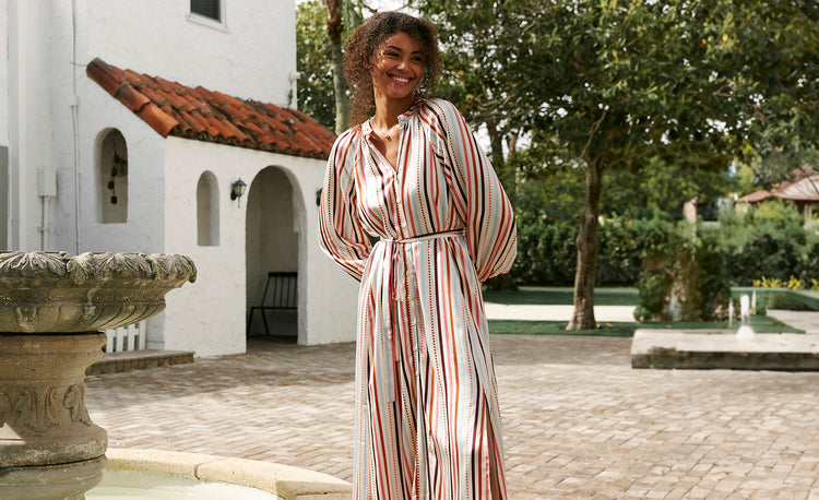 Woman Sitting by the Fountain Wearing Lemlem Makeda Button Up Dress in Bizu Cream Color