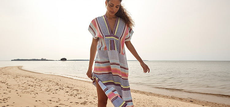 Woman walking on the beach in the Gasira Cirq Citron long caftan dress