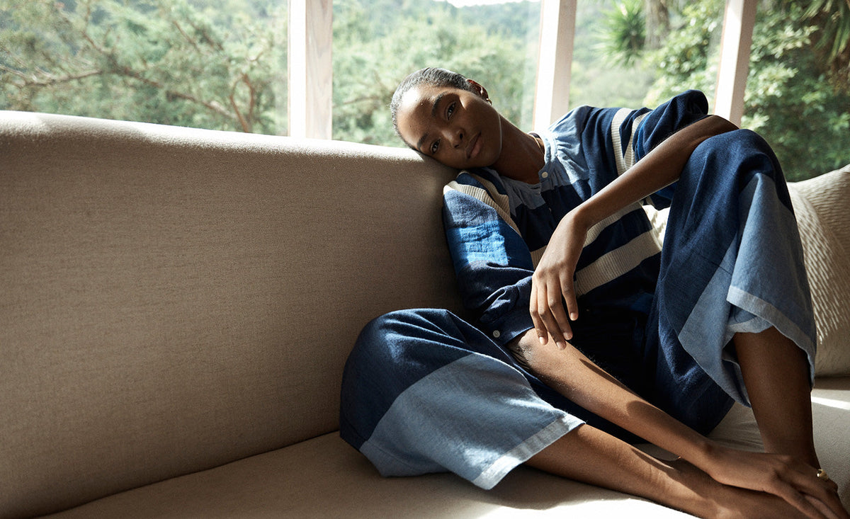 Woman Sitting on the couch wearing desta pants featuring color block pattern in blue colors and a blouse