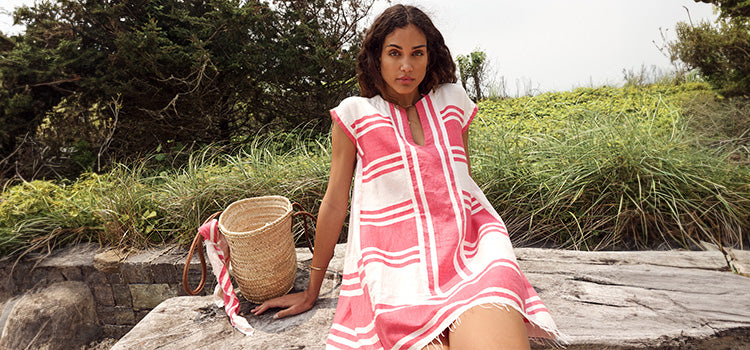 woman sitting on a wooden bench in a garden wearing the Ayelu Fragaria Elina caftan dress