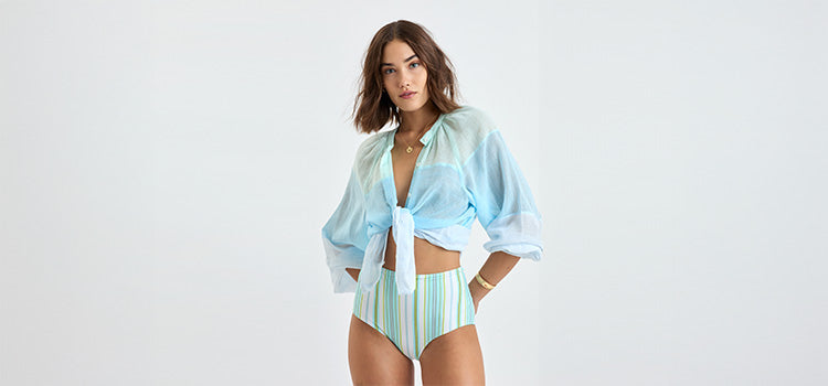 Woman Standing wearing lemlem bikini swimsuit featuring stripe pattern in multicolor on cream background