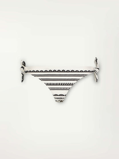 Product Front Shot of a Lucy Side Tie Bikini Bottom  featuring intricate black Tibeb bands on a textured white background.