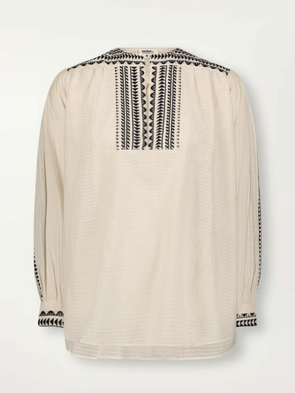 Product Front Shot of Dera Blouse featuring intricate black Tibeb bands on a textured vanilla background.