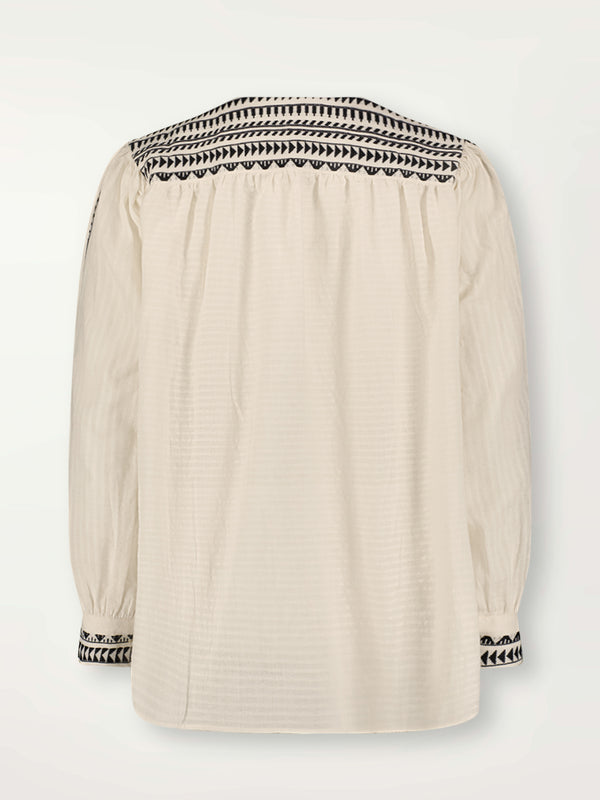 Product Back Shot of Dera Blouse featuring intricate black Tibeb bands on a textured vanilla background.