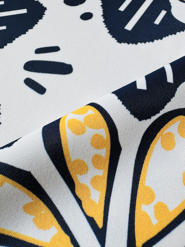 Close up on lemlem swim fabric featuring exclusive in-house–designed floral prints accented by ancient motifs, rendered in bright yellow and navy on an ivory background.