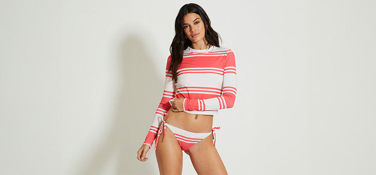 Woman Standing Wearing lemlem rashguard and string bottom featuring color block pattern in watermelon and white colors