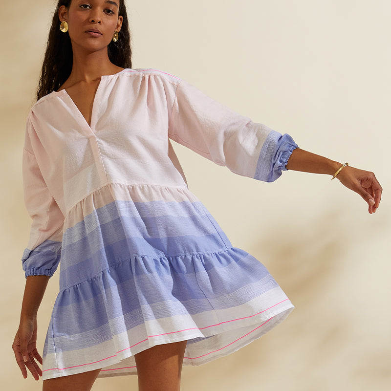 Woman twirling in  a short soft pink and blue flutter dress.