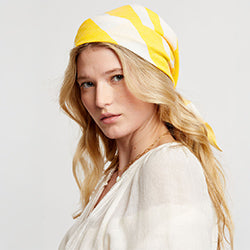 Woman standing wearing lemlem handwoven DANA Bandana featuring striped pattern in yellow and beige colors