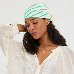 Woman wearing a green and white striped headband against a white background