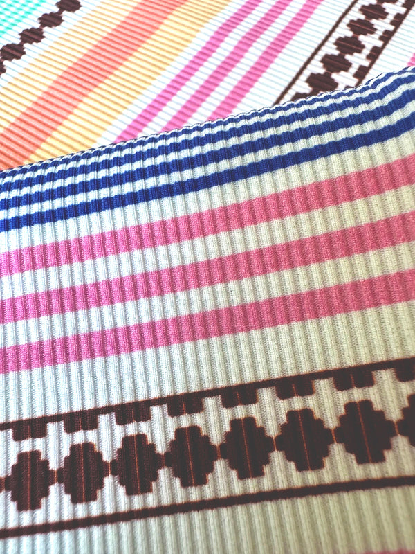close up on lemlem cirq swim fabric featuring intricate stripes in sun-washed hues and a Tibeb-inspired pattern in rich dark plum