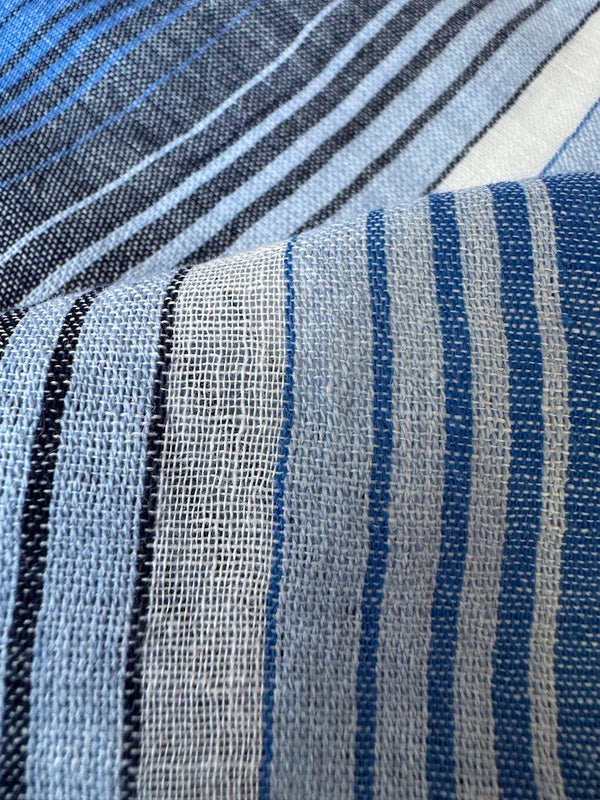 close up on lemlem handwoven fabric featuring  stripe pattern that blends into a stunning ombré effect, with soft transitions between white, sky blue, mid blue, and deep navy.
