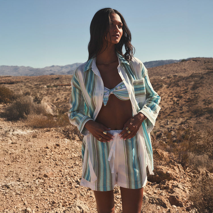 Woman in a striped outfit standing in a desert landscape