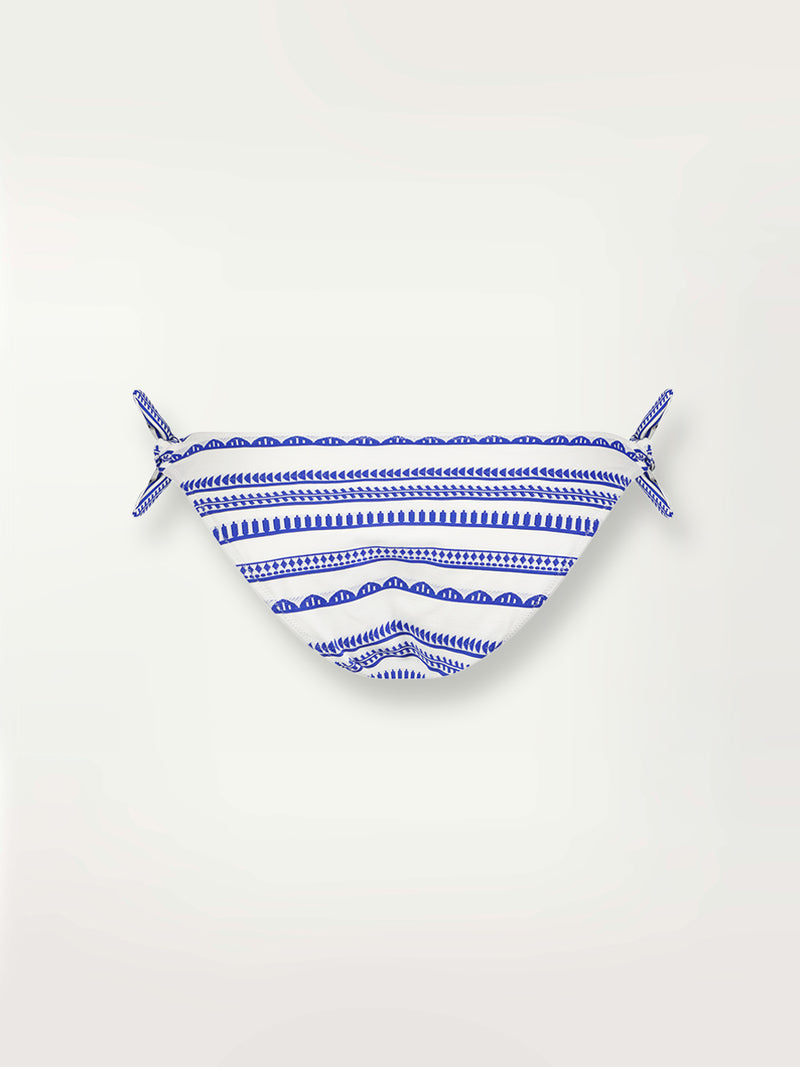 Product shot of the back the Yani Side Tie Bikini Bottom featuring blue tibeb diamond design bands on a textured seersucker white background.  