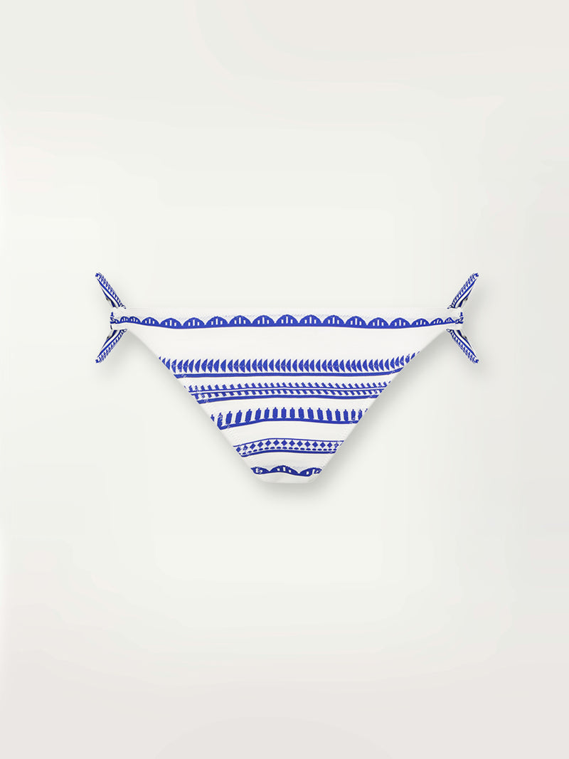 Product shot of the Yani Side Tie Bikini Bottom featuring blue tibeb diamond design bands on a textured seersucker white background.  
