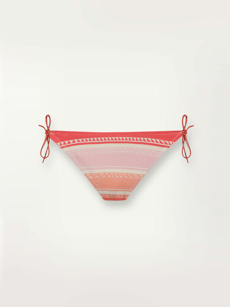 Product shot of the Eshal String Bikini Bottom featuring white doted stripes with gradiant orange and tangerine bands on a lilac and white background.
