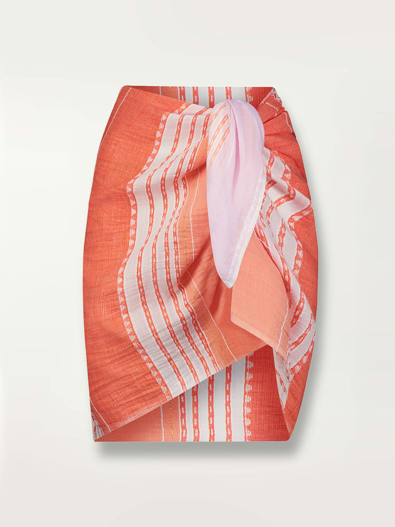 Product shot of the Eshal Sarong featuring white doted stripes with gradiant orange and tangerine bands on a lilac and white background.