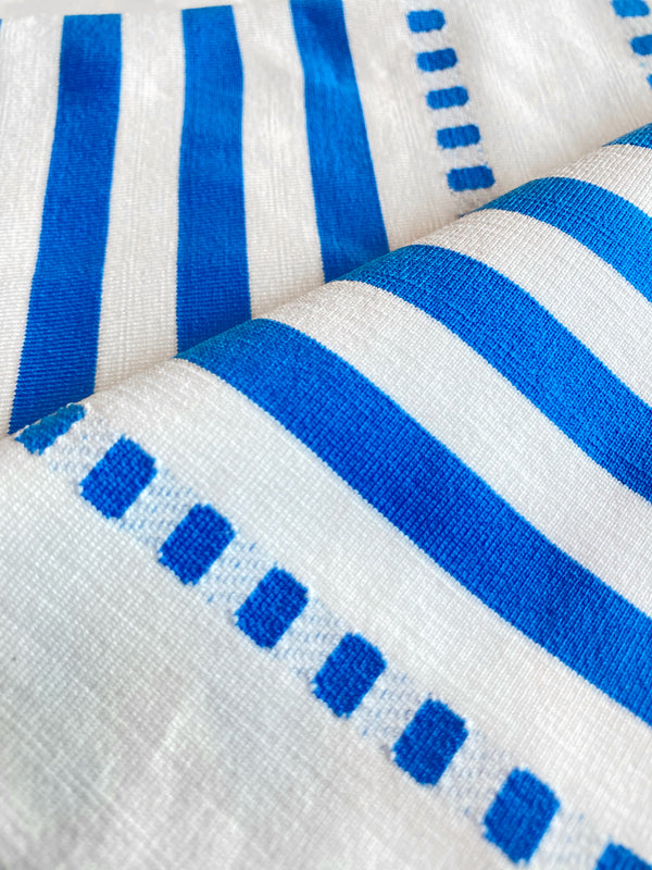 Close Up on Eshe Blue Fabric Featuring crisp white background and bright blue stripes and dots pattern and a matching brief bikini bottom