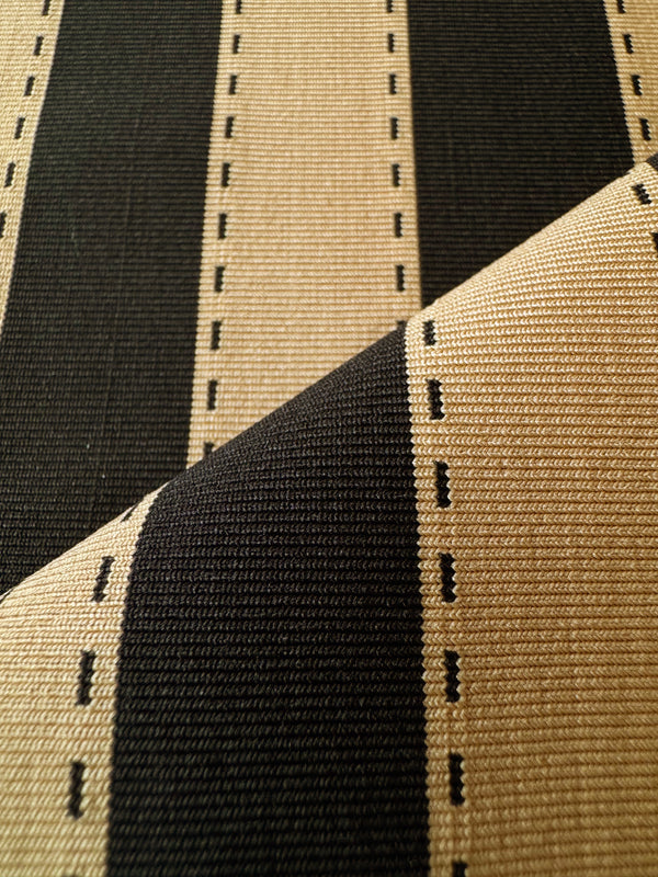 Close-up of a lemlem debre sand swim textile with bold vertical stripes in black and warm beige, featuring small dashed line accents between the stripes.
