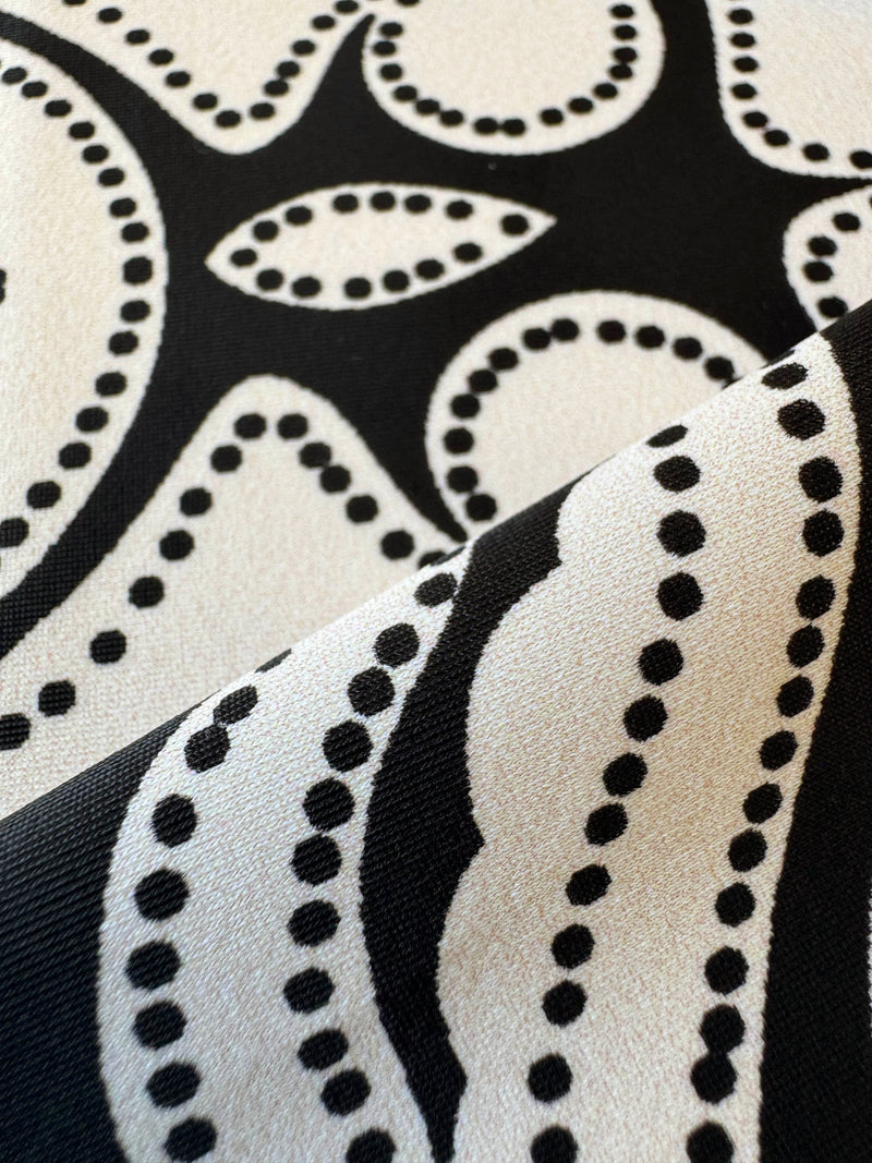 close up on lemlem niku black fabric featuring ancient inspired pattern in creamy ivory perfectly grounded by rich black for a striking and timeless look.
