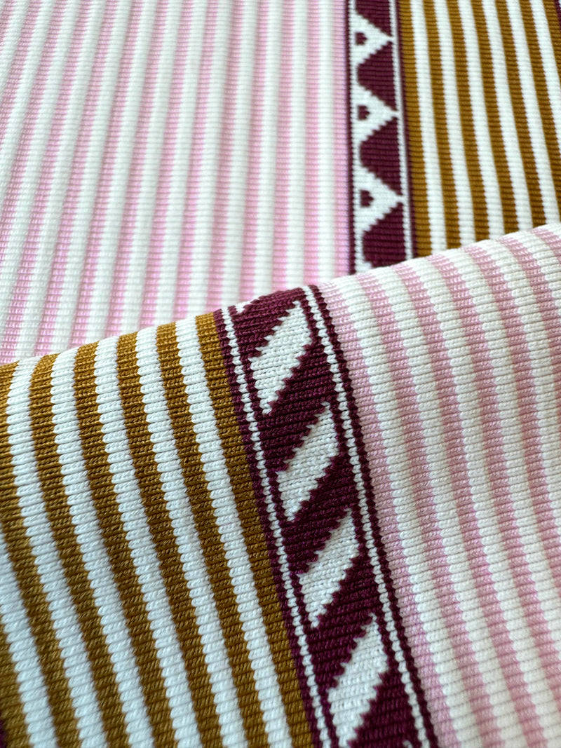 close up on lemlem swim fabric featuring detailed bands of deep burgundy, bronze, and pink stripes beautifully placed on a light cream 