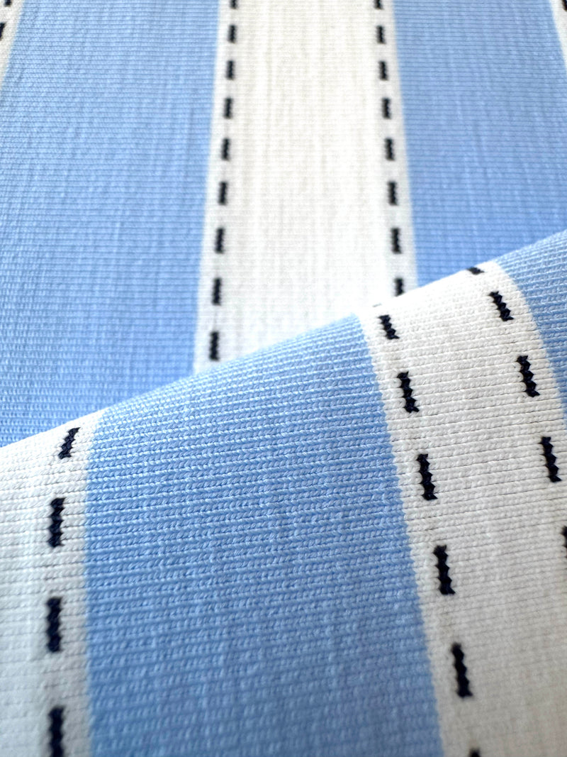 Close up on lemlem Debre Sky swim fabric featuring bold, crisp white stripes on a sky-blue background, accented with black detailing.