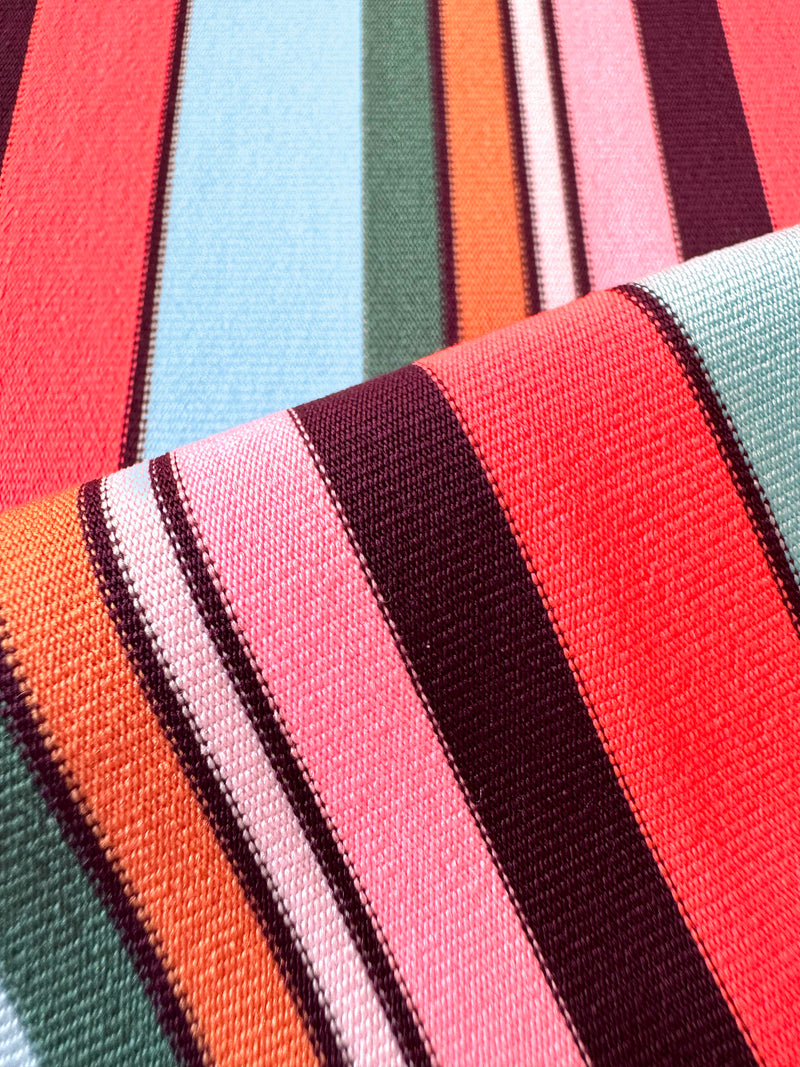 Close up on lemlem swim poppy sunset fabric featuring color block stripe pattern in white on sky blue background