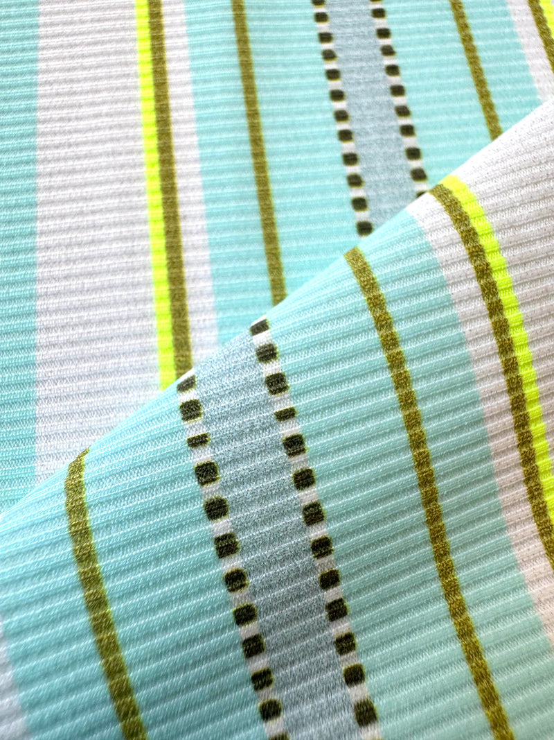 Close up on lemlem genet mint fabric featuring a chic stripe pattern in aqua blue and sage tones, delineated by dark olive dots and accented with a splash of neon yellow on a cream background.