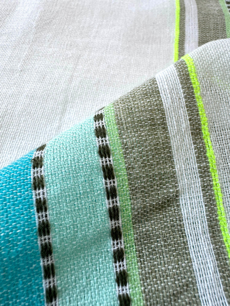 Close up on lemlem genet mint fabric featuring a chic stripe pattern in aqua blue and sage tones, delineated by dark olive dots and accented with a splash of neon yellow on a cream background.